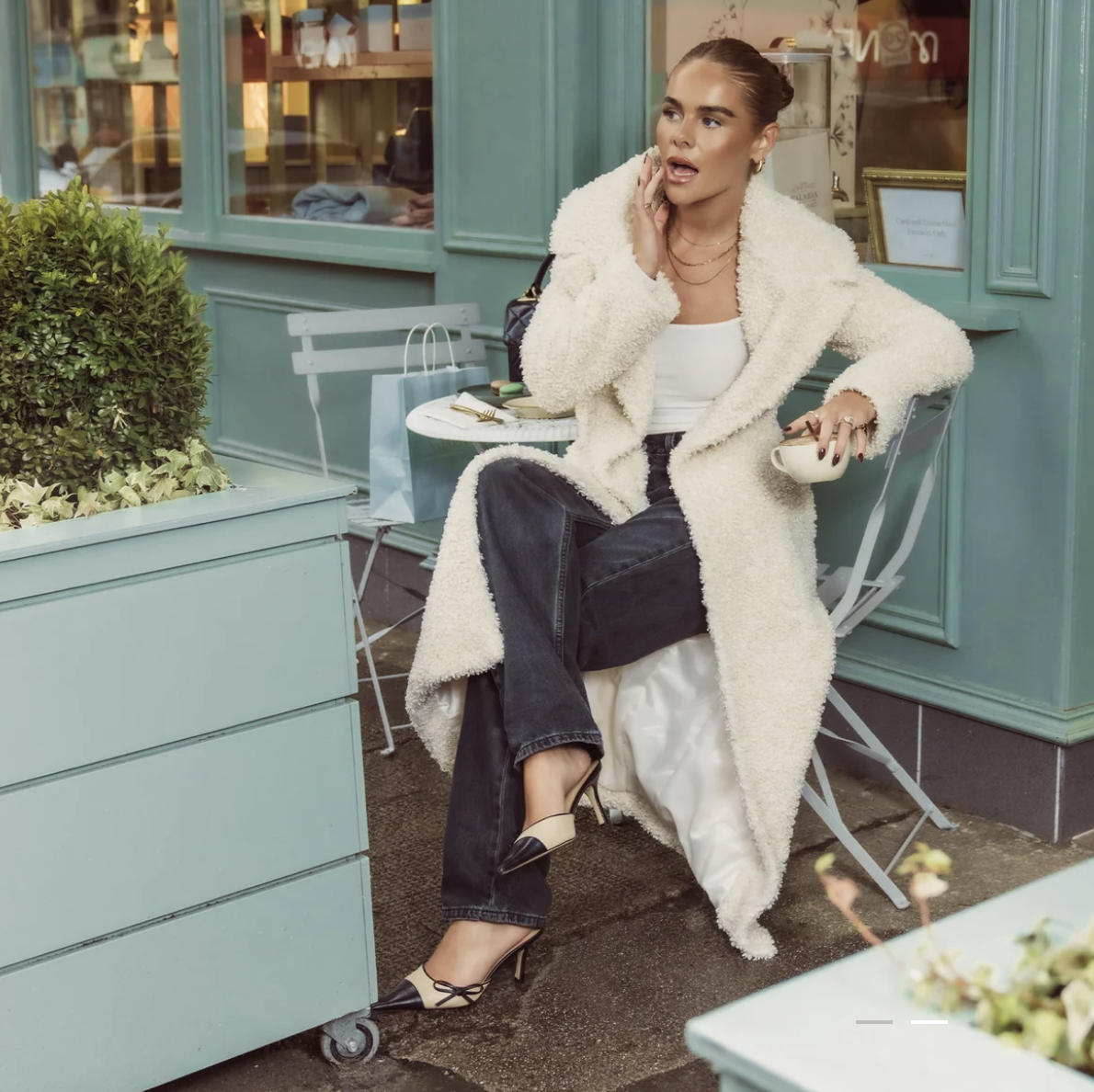 Model sitting in furry jacket enjoying coffee